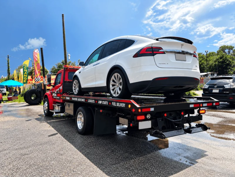 White electric SUV loaded on a Special Lane Towing Services flatbed tow truck